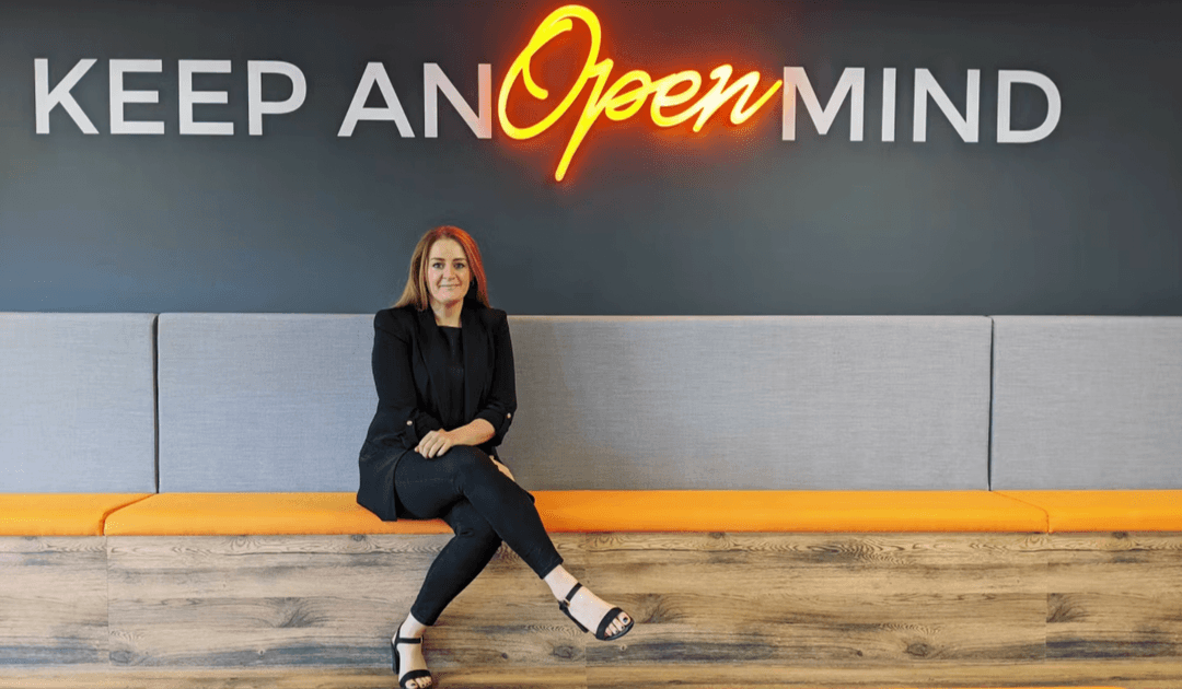 Laura herbert under a sign saying 'keep an open mind'