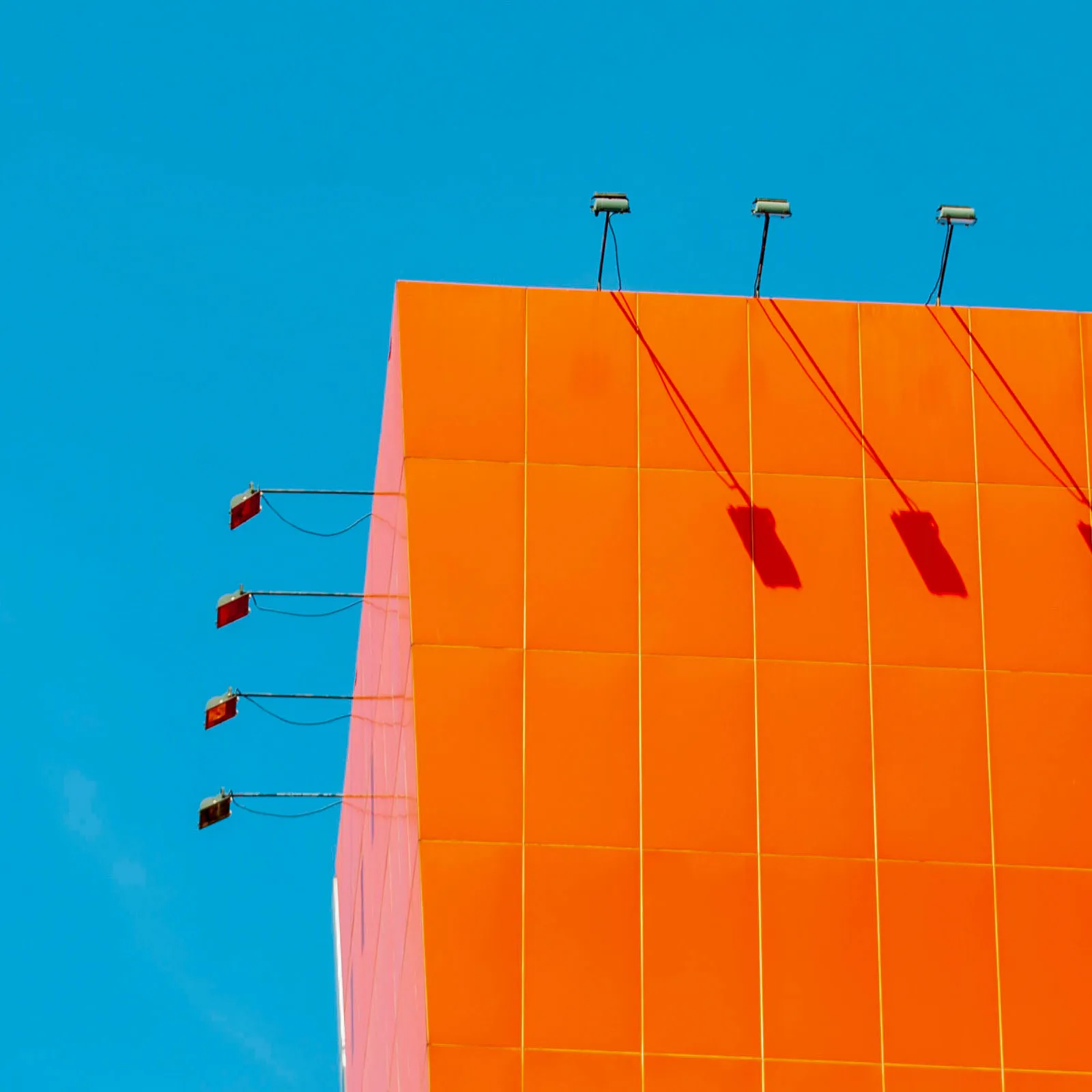 Corner of an orange building against a bright, blue sky.
