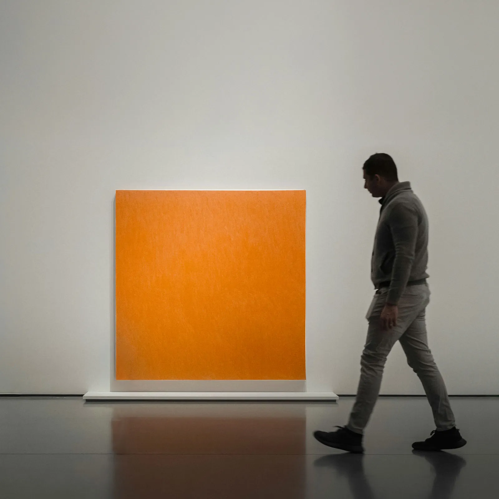 A man walking in front of a large orange square.