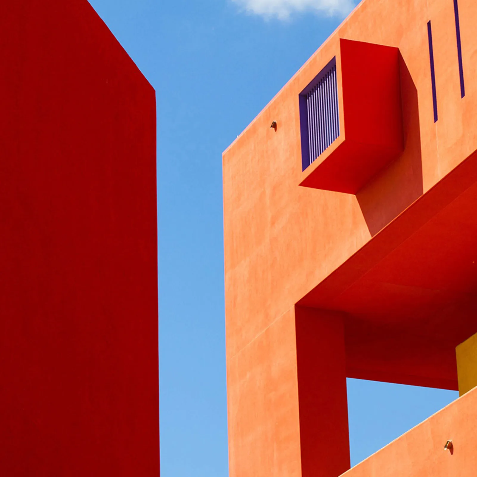 The corner of an orange building against a bright blue sky.