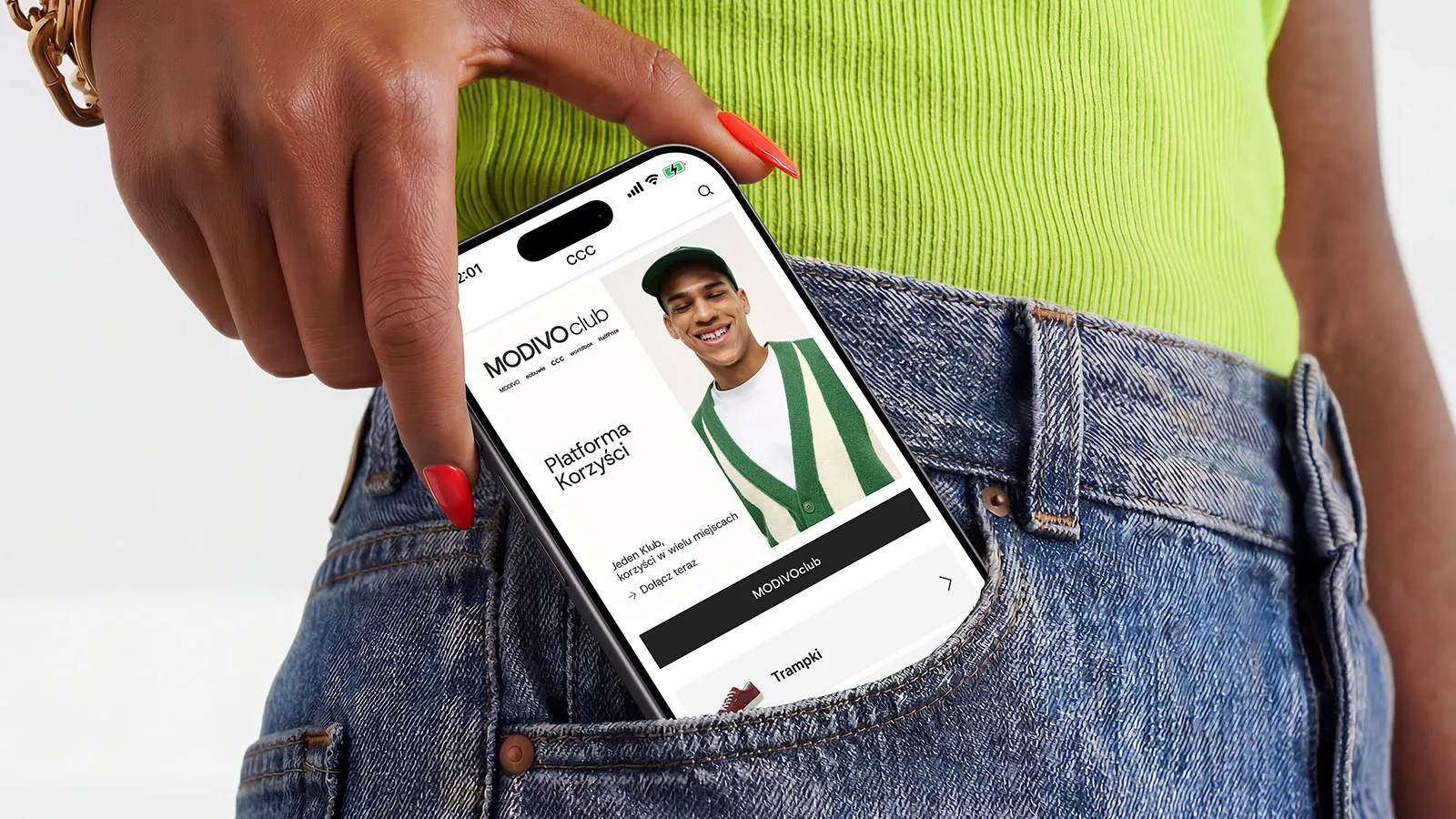 A woman's hand reaches into the top pocket of her blue jeans, pulling out a phone displaying the CCC app.