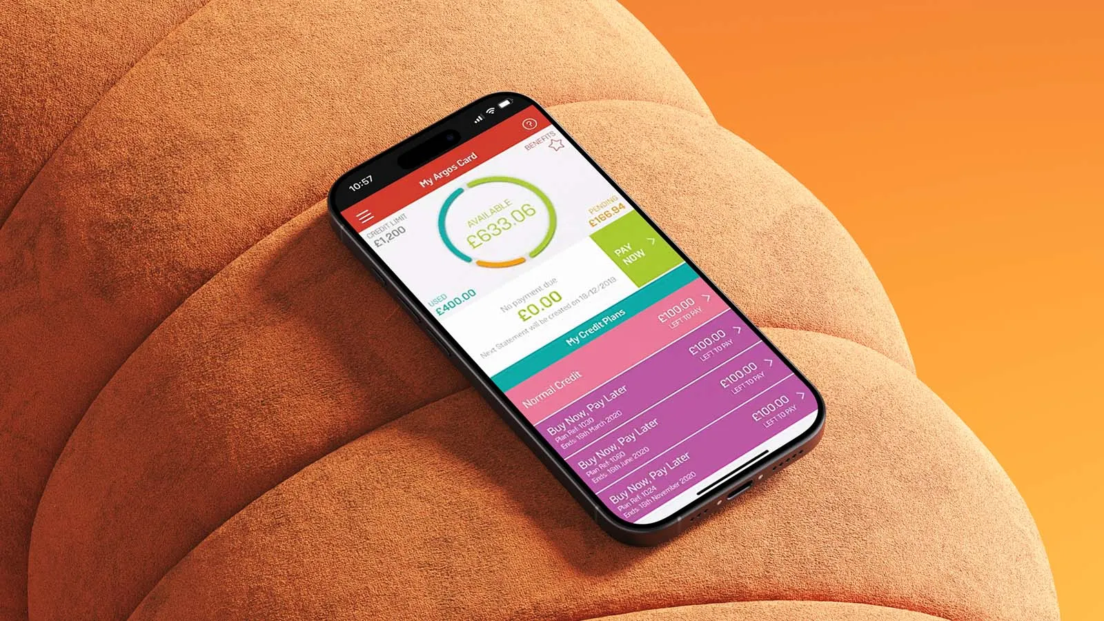 A mobile phone displaying the My Argos Card app lying an orange sofa.