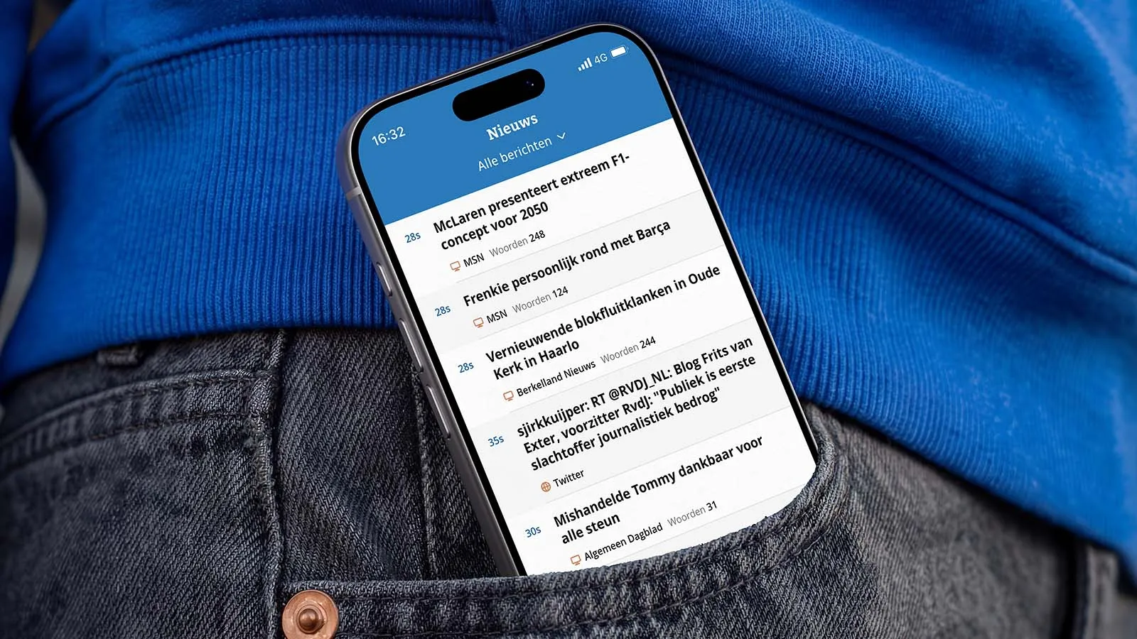 Smartphone showing a Dutch news feed rests in the pocket of dark jeans beneath a bright blue shirt, conveying everyday digital news use.