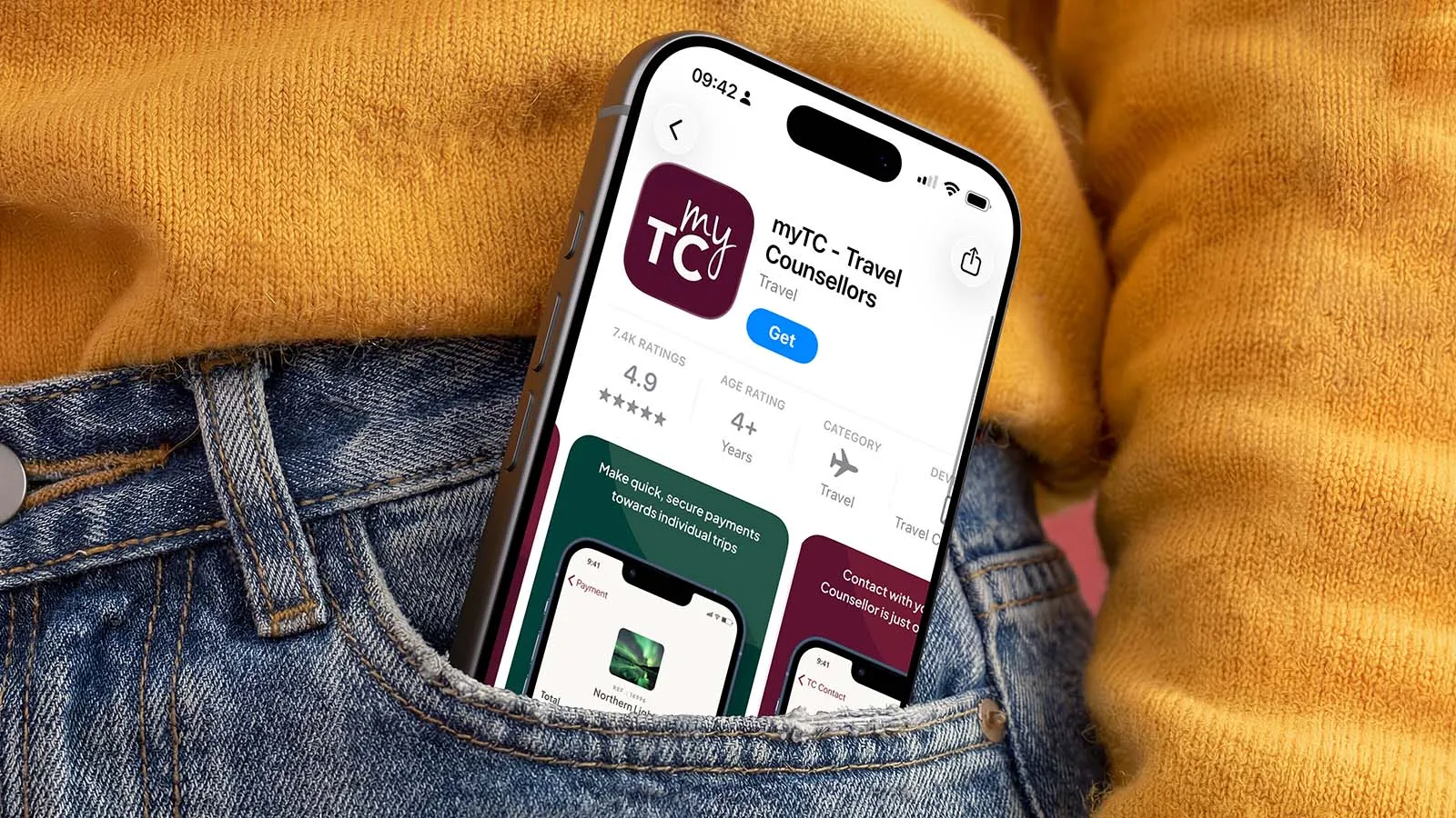 Smartphone showing the myTC travel app rests in a jeans pocket, framed by a mustard sweater.