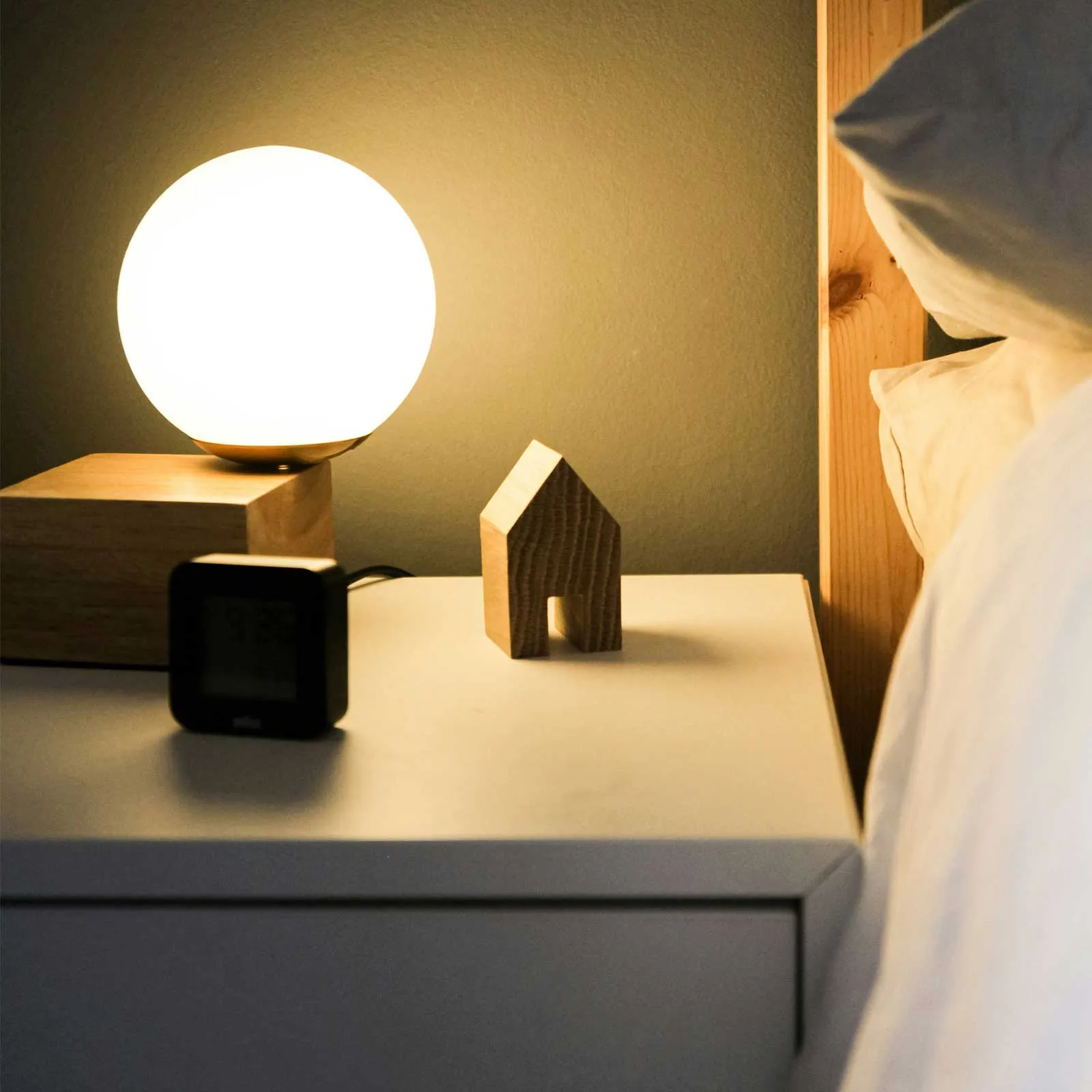 Bedside table with a glowing lamp beside a bed, creating a warm nighttime setting for sleep monitoring.